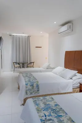 a bedroom with two beds and a table at Hotel Coral Reef Cartagena in Cartagena de Indias
