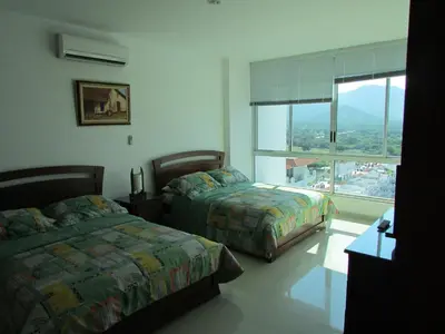 a bedroom with two beds and a large window at Costa Azul Suites 1002 in Santa Marta