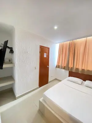 a white room with a bed and a door at Hotel Cartagena Premium in Cartagena de Indias