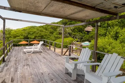 a deck with white chairs and a table at Hotel Playa Scondida Barú in Baru
