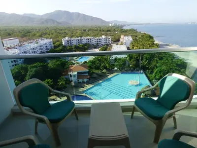 a balcony with two chairs and a swimming pool at Costa Azul Suites 906 in Santa Marta