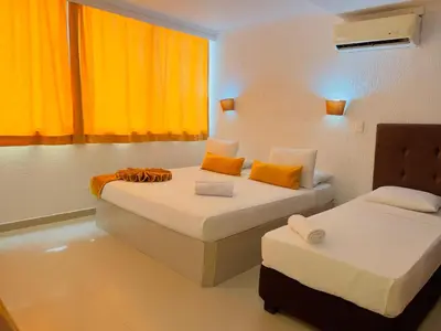 two beds in a room with orange curtains at Hotel Costa del Sol in Cartagena de Indias