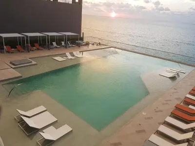 a swimming pool with lounge chairs and the ocean at Morros City - Frente al mar in Cartagena de Indias
