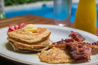a plate with pancakes and bacon on a table at Casa Claver Loft Boutique Hotel in Cartagena de Indias