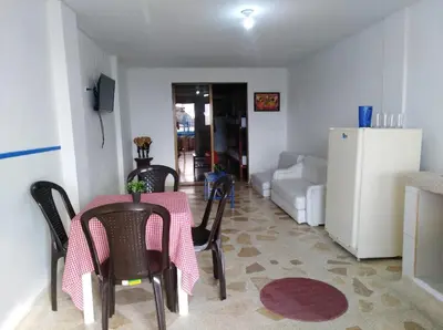 a living room with a table and chairs and a refrigerator at Cabañas Cigua in Coveñas