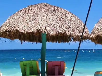 two chairs under a straw umbrella on the beach at The Wizard & Bar BARU in Playa Blanca
