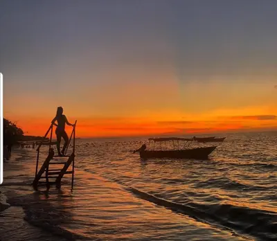 a person standing on a stand on the beach with a boat at The Wizard & Bar BARU in Playa Blanca