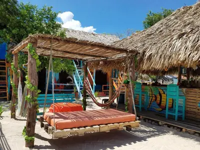 a swinging bed in front of a thatched house at The Wizard & Bar BARU in Playa Blanca