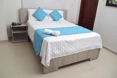 a bedroom with a large bed with blue pillows at Hotel Dainner in Plato
