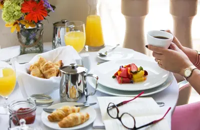 a table with plates of food and a person holding a cup of coffee at Movich Hotel Cartagena de Indias in Cartagena de Indias