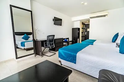 a hotel room with two beds and a desk at Hotel Cartagena Plaza in Cartagena de Indias