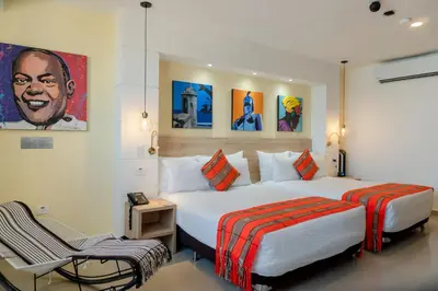 a hotel room with two beds and a chair at Hotel Cartagena Plaza in Cartagena de Indias