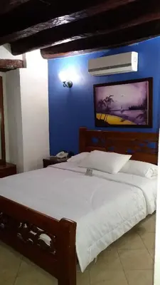 a bedroom with a large white bed with a blue wall at Hotel Don Pedro De Heredia in Cartagena de Indias