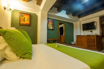 a bedroom with a large bed with a green blanket at Hotel Don Pedro De Heredia in Cartagena de Indias