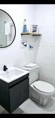 a white bathroom with a toilet and a sink at Edificio Marina del Rey Cartagena in Cartagena de Indias
