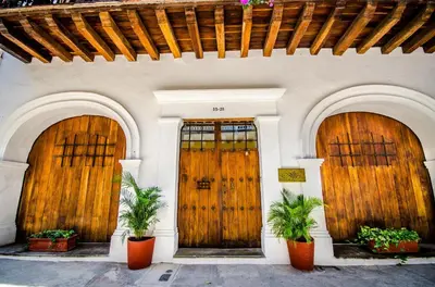 three wooden doors on a building with potted plants at Alfiz Hotel in Cartagena de Indias