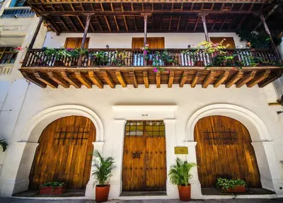 a building with a balcony with wooden doors and plants at Alfiz Hotel in Cartagena de Indias