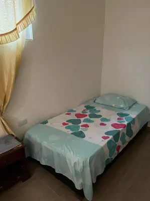a small bedroom with a bed with a floral bedspread at Casa Vecchio in Cartagena de Indias
