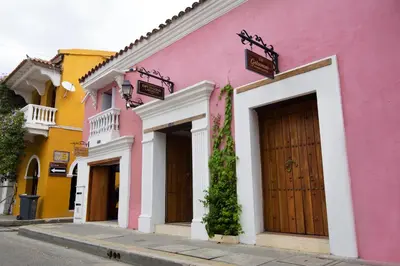 a pink building with a wooden door on a street at Life is Good Cartagena Hostel in Cartagena de Indias