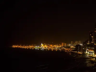 a city lit up at night with the water at Hotel Capilla del Mar in Cartagena de Indias