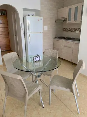 a glass table and chairs in a kitchen with a refrigerator at Apartamento con hermosa vista y cerca de playas in Cartagena de Indias