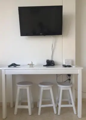 a white desk with two stools and a television on a wall at Apartamento con hermosa vista y cerca de playas in Cartagena de Indias