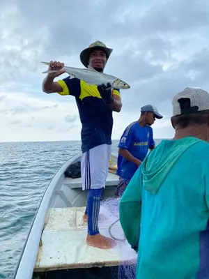 a man standing on a boat holding a surfboard at Galerazambahostal in Galerazamba
