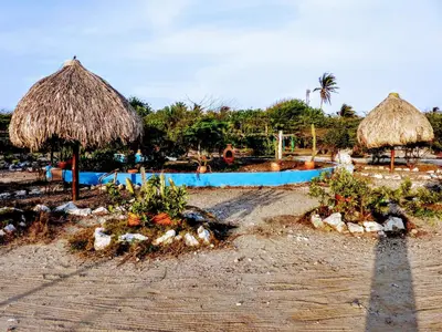 two straw umbrellas and a swimming pool on a beach at Galerazambahostal in Galerazamba