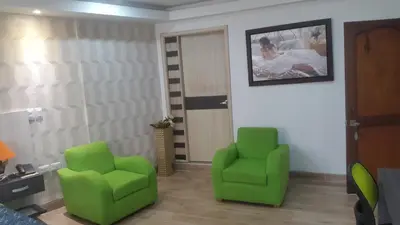a living room with two green chairs and a door at Hotel Damys in Sincelejo