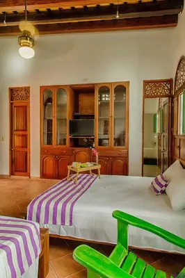 a bedroom with a large bed and two green chairs at Casa D´Remedios La Bella Hotel Boutique in Ciénaga