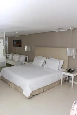 a bedroom with a large white bed with white pillows at Country International Hotel in Barranquilla
