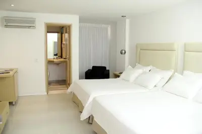 a hotel room with two beds and a chair at Country International Hotel in Barranquilla