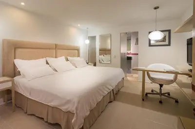 a bedroom with a large white bed and a desk at Country International Hotel in Barranquilla