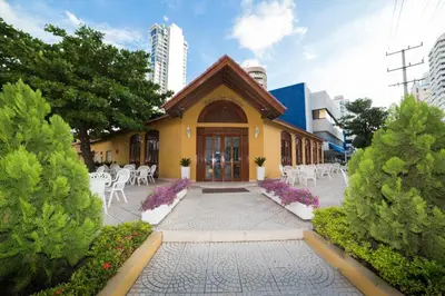 a yellow building with white chairs and tables and trees at San Martin Cartagena in Cartagena de Indias