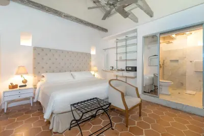 a bedroom with a large white bed and a chair at El Marques Hotel Boutique By GEH Suites in Cartagena de Indias