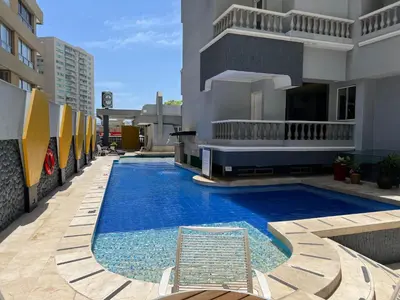 a swimming pool with a chair next to a building at Hotel American Golf in Barranquilla