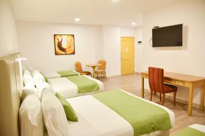 a hotel room with two beds and a desk and a television at Hotel American Golf in Barranquilla