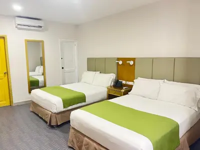 a hotel room with two beds and a mirror at Hotel American Golf in Barranquilla