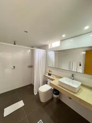 a bathroom with a white toilet and a sink at Hotel American Golf in Barranquilla