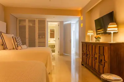 a bedroom with two beds and a flat screen tv at Casa La Merced by Mustique in Cartagena de Indias