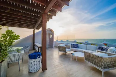a patio with a couch and chairs and the ocean at Casa La Merced by Mustique in Cartagena de Indias