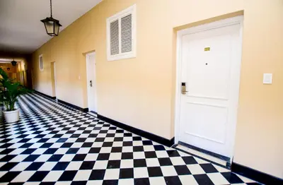 a hallway with a checkered floor and a white door at Hotel El Prado in Barranquilla
