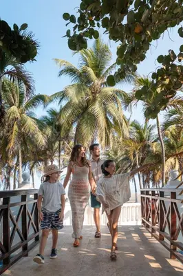a group of people walking on a bridge with palm trees at Hotel Las Americas Casa de Playa in Cartagena de Indias