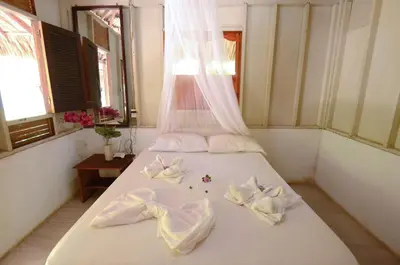 a bedroom with a white bed with bows on it at Isla Grande Eco-Hostal in Isla Grande