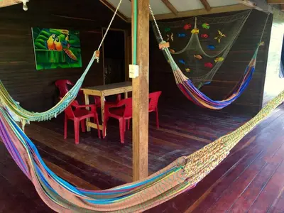 a room with two hammocks and a table and chairs at Isla Grande Eco-Hostal in Isla Grande
