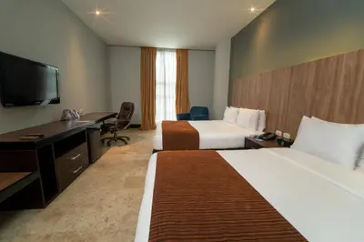a hotel room with two beds and a desk and a television at GHL Hotel Barranquilla in Barranquilla