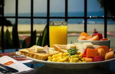 a plate of breakfast food and a glass of orange juice at GHL Relax Hotel Costa Azul in Santa Marta