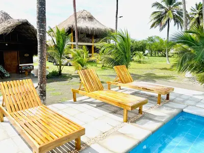 three wooden chairs sitting next to a swimming pool at Ecohotel Kocoluu in San Bernardo del Viento