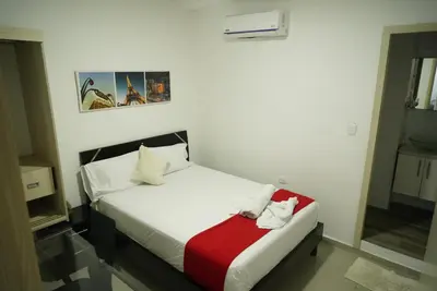 a bedroom with a white bed with a red blanket at Hotel Sun River in Barranquilla