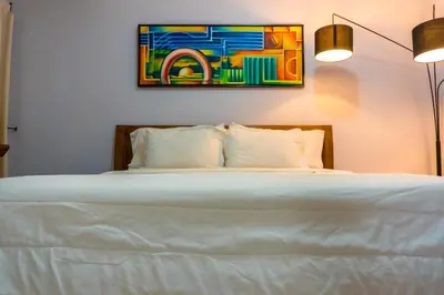 a bedroom with a white bed with a painting on the wall at Hotel Casa La Tablada Manga in Cartagena de Indias